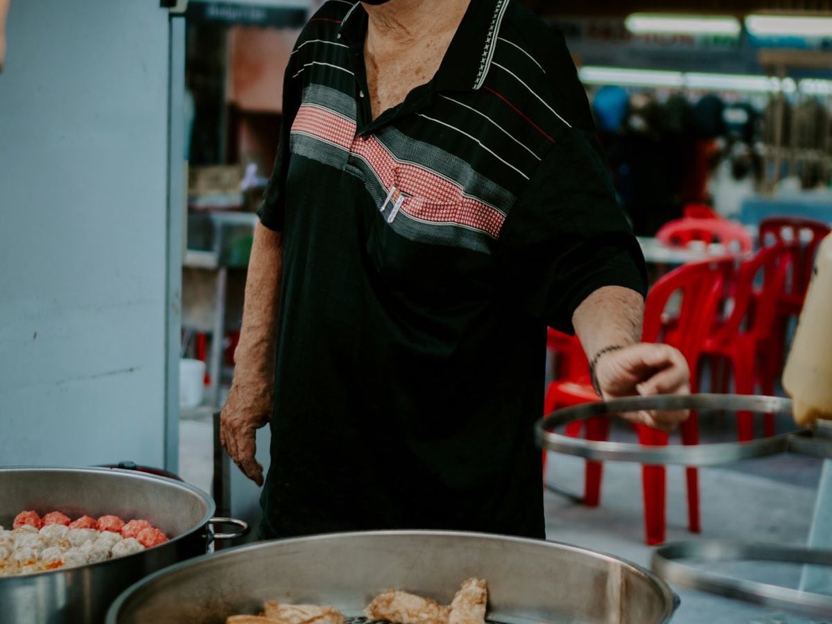 A street-food vendor serving from steaming pots at a Kuala Lumpur night stall