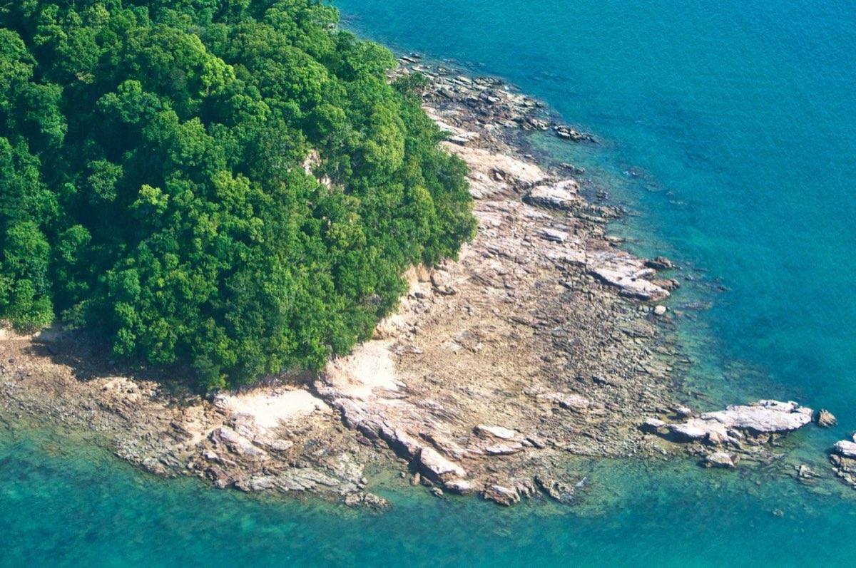 Aerial view of a forested Langkawi island ringed by turquoise water
